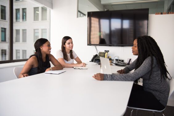 3 women sitting at a table in a conference room